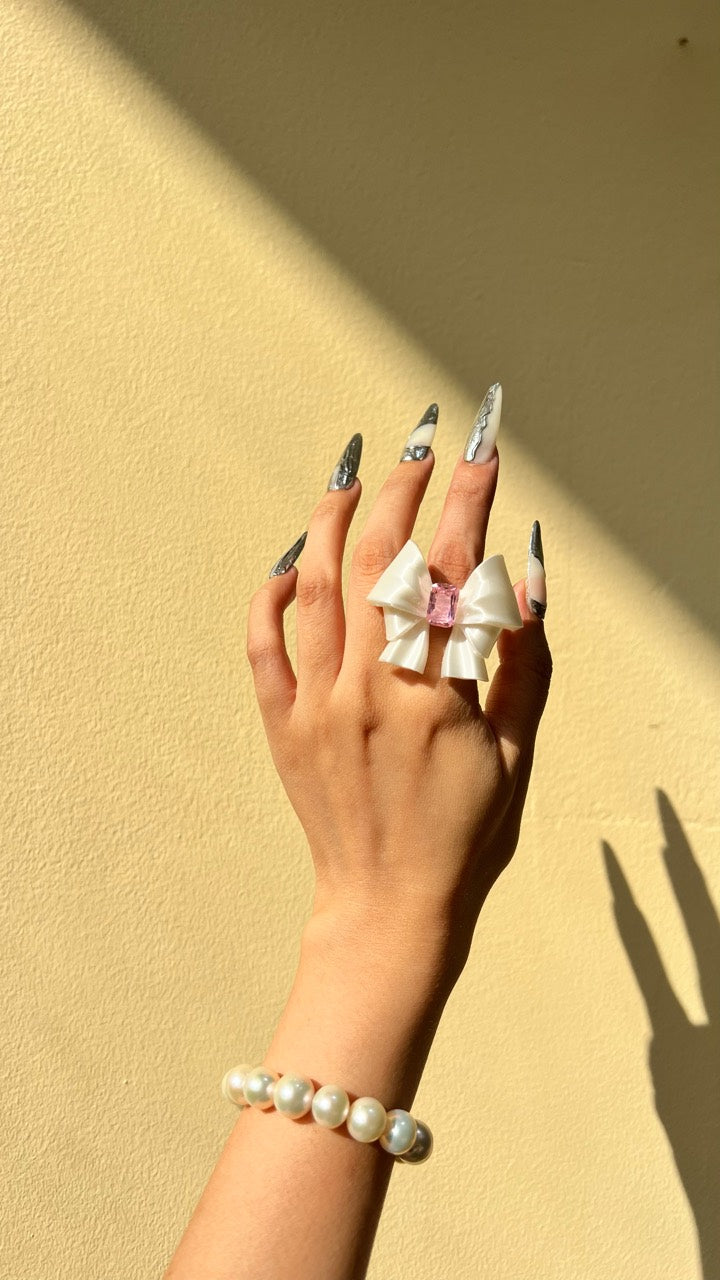 White bow ring worn on a hand