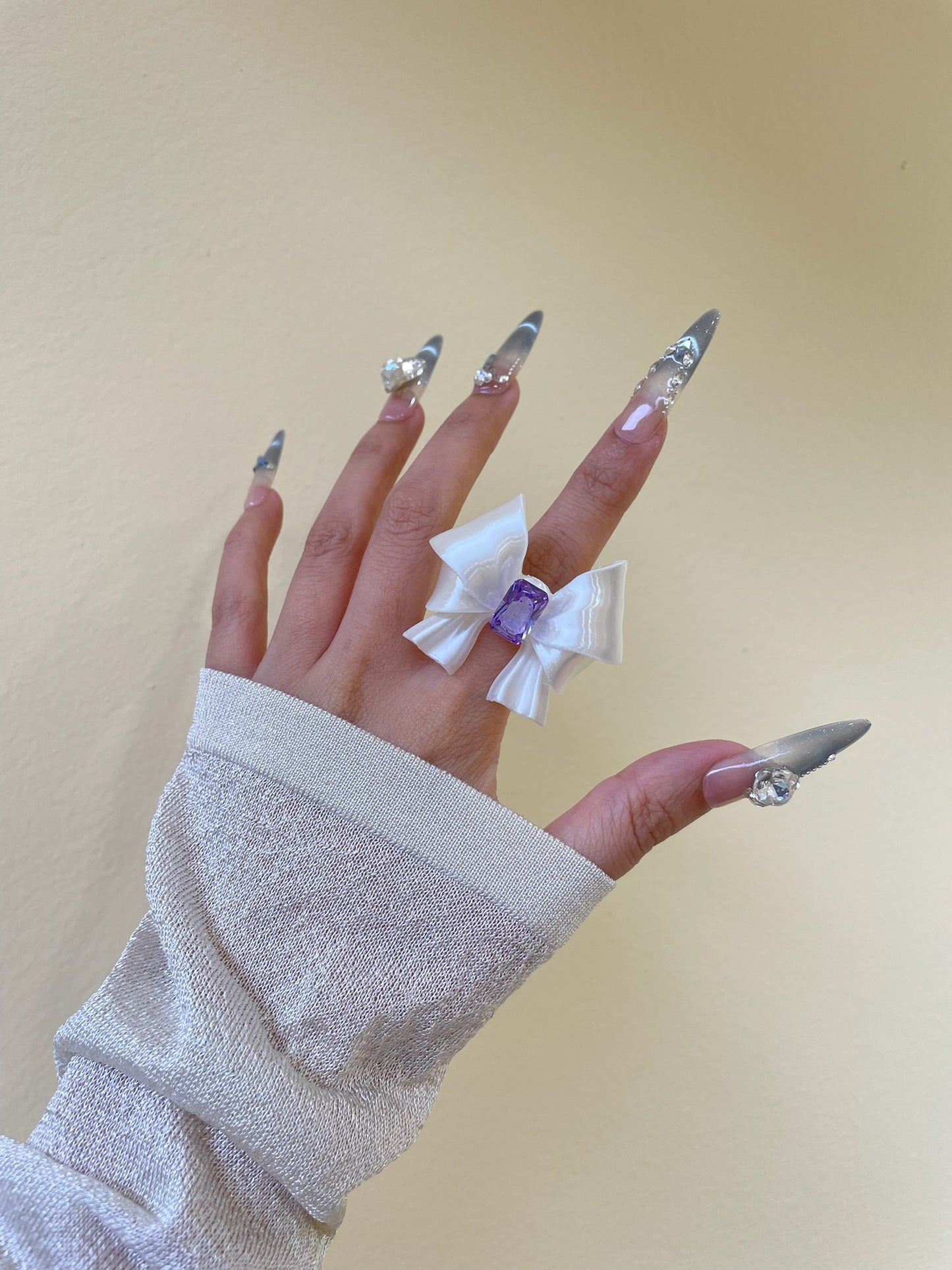 Silk White Ribbon Bow Ring with purple cubic zirconia on display by UNICOLOOM